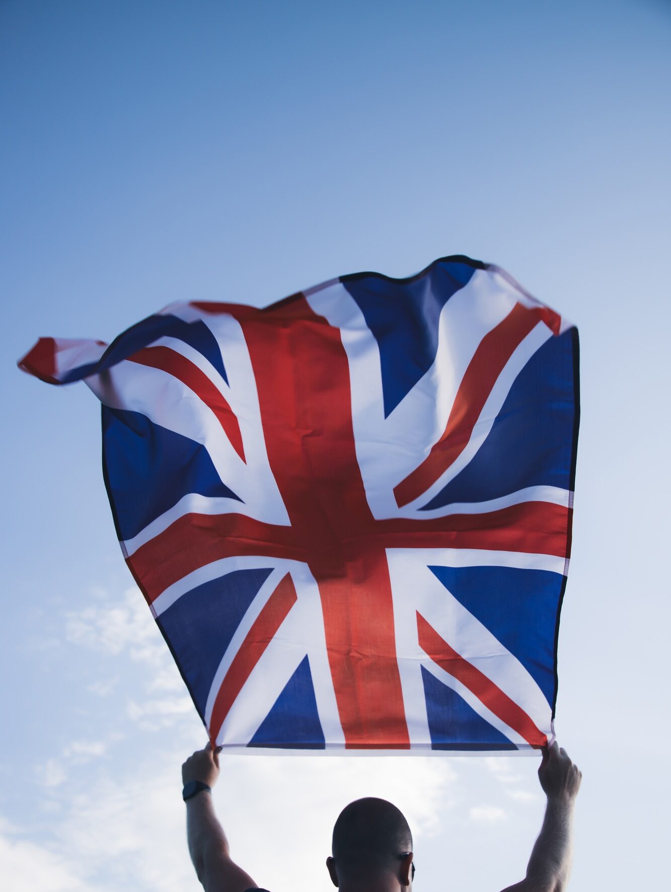 Man holding British flag against blue sky