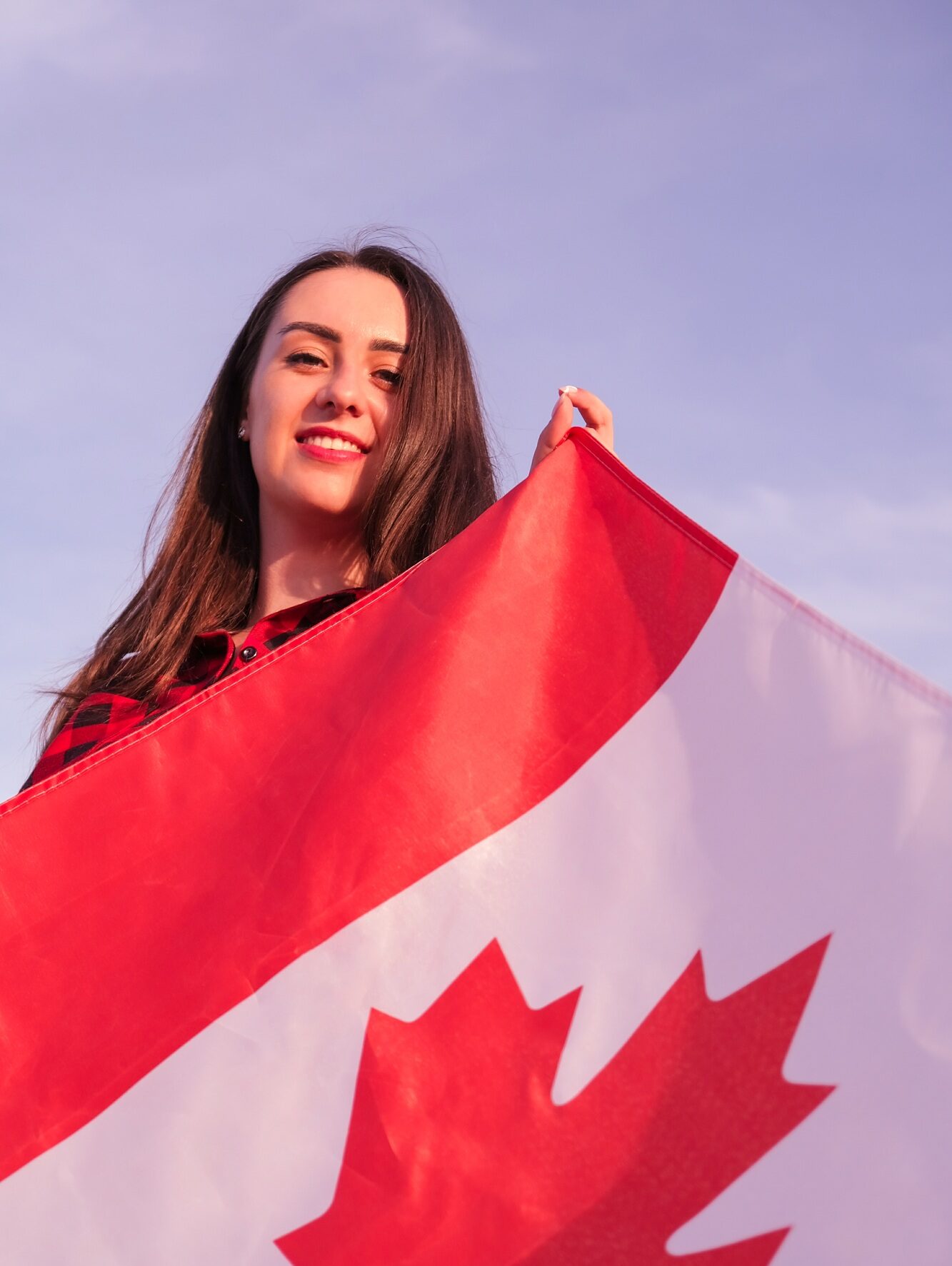 Young millennial brunette woman holding The National Flag of Canada. Canadian Flag or the Maple Leaf